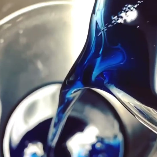 Blue oil being poured into a glass beaker in the making of Blue Opal Solid Serum by Precious Skin Elixirs natural skincare