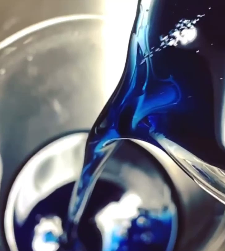 Blue oil being poured into a glass beaker in the making of Blue Opal Solid Serum by Precious Skin Elixirs natural skincare